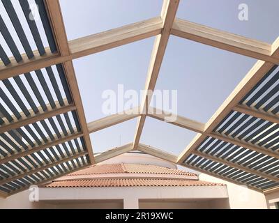 Moderno design trendy tetto triangolare, baldacchino all'aperto con fori di travi con tavole contro il sole. Foto Stock