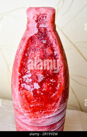Fragole fritte rosse, gelate e saporite. Fragole fritte surgelate e brillanti sotto forma di bottiglia tagliate su fondo beige. Foto Stock