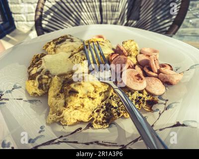 Omelette con salsiccia e una tazza di latte servita per colazione in un ristorante Foto Stock