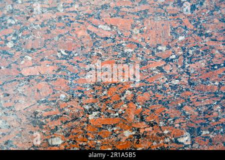 Texture di un muro di pietra costoso granito forte liscio forte e lussuoso, chip di marmo bicolore nero-e-marrone inframezzato. Lo sfondo. Foto Stock