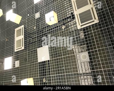 La struttura del soffitto industriale dell'edificio con una griglia metallica e ventilazione di lampade, lampade in stile loft. Lo sfondo. Foto Stock