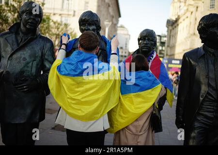 I tifosi che mettono una bandiera Ukrainan sulla Statua dei Beatles a Pier Head a Liverpool in vista della finale dell'Eurovision Song Contest alla M&S Bank Arena di sabato. Data immagine: Venerdì 12 maggio 2023. Foto Stock