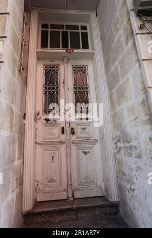 29 novembre 2024, Kuzguncuk, Istanbul, Turchia: Doppia porta in legno bianco intemprato con griglie in ferro ornate e numero civico 40, incastonata nella facciata in pietra Foto Stock