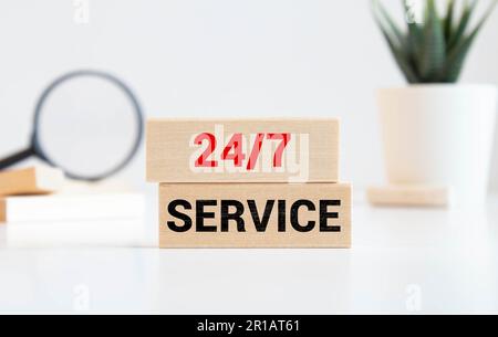 Aperto 7 giorni su 7, 24 ore su 24. 24-7 segno verde che funziona intorno all'orologio appeso su una parete scura. Negozio funzionante 24 ore su 24, cartello sulla facciata della costruzione Foto Stock