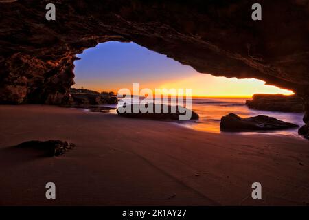 Alba alba dall'interno della grotta marina sulla spiaggia di Caves in Australia - mare panoramico della costa del Pacifico. Foto Stock