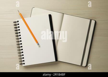 Notebook e matita su tavolo di legno bianco, vista dall'alto Foto Stock