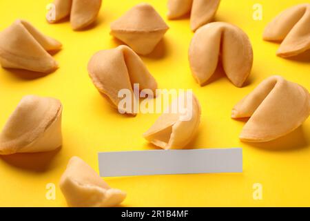 Molti biscotti gustosi della fortuna con le previsioni sullo sfondo giallo, primo piano. Spazio per il testo Foto Stock