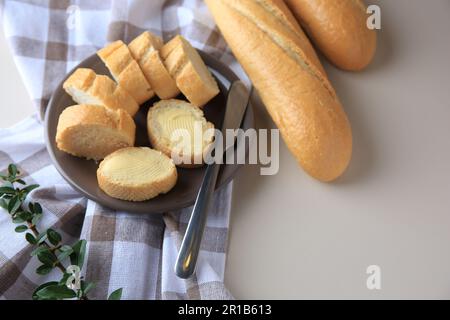 Baguette intere e tagliate con burro fresco in tavola Foto Stock