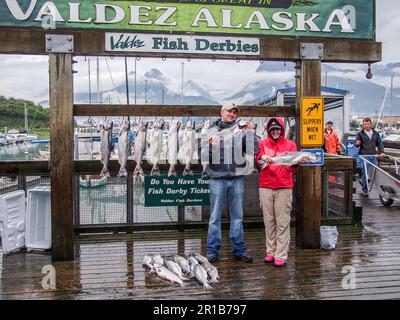 Due persone felici che mostravano il salmone d'Argento (Oncorhynchus kisutch) catturati in un derby da pesca a Valdez, Alaska. Foto Stock