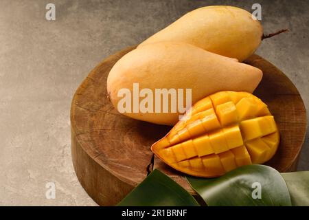 Cubetti di fettine di mango giallo e mango su legno con fondo di legno. Frutta di mango orizzontale. Foto Stock