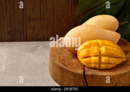 Cubetti di fettine di mango giallo e mango su legno con fondo di legno. Frutta di mango orizzontale. Foto Stock