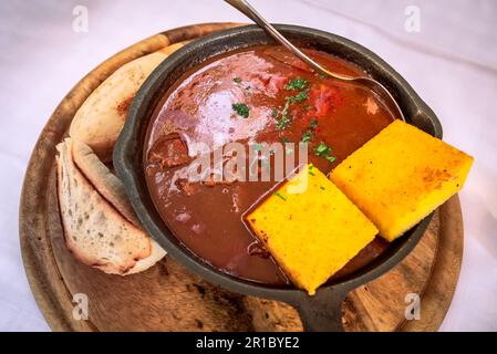 Gulyas, piatto tradizionale ungherese, stufato sostanzioso a base di manzo o maiale, cipolle, paprika, pomodori e spezie varie. Taverna estiva in Slovenia. Foto Stock