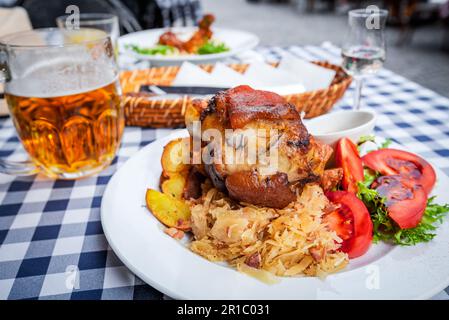 Zeppa di maiale al forno con birra, cavolo bavarese e aglio, patate al prezzemolo bistecca, Schweinshaxe. Foto Stock