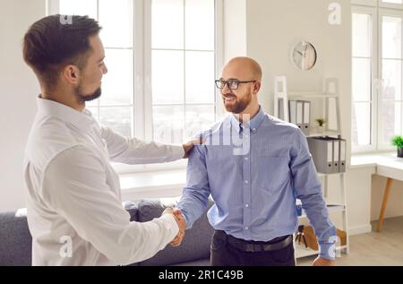Due uomini d'affari che scuotono le mani durante la riunione in ufficio Foto Stock