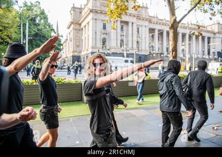 I manifestanti neonazisti salutano perché sono ordinati a lasciare la zona durante la manifestazione. Una giornata di tensioni politiche e scontri si è svolta a Melbourne in quanto un gruppo di estrema destra dei neonazisti ha organizzato un raduno anti-immigrazione presso il parlamento di stato, ha incontrato una feroce opposizione da parte di controppositori antifascisti di sinistra. La polizia antisommossa è stata dispiegata mentre scuffi scoppiavano tra i due gruppi, con lo spray al pepe e i cavalli utilizzati per controllare la folla. I segnali di protesta che chiedevano inclusività, diversità e giustizia sociale sono stati tenuti in alto in una dimostrazione di unità contro il discorso dell’odio e la discriminazione. Gli scontri sono molto alti Foto Stock