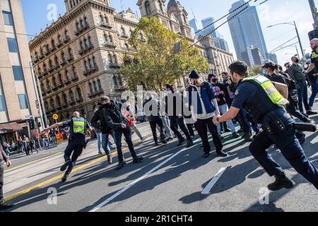 Un poliziotto insegue un protettore antifascista che gli ha gettato un oggetto durante la manifestazione. Una giornata di tensioni politiche e scontri si è svolta a Melbourne in quanto un gruppo di estrema destra dei neonazisti ha organizzato un raduno anti-immigrazione presso il parlamento di stato, ha incontrato una feroce opposizione da parte di controppositori antifascisti di sinistra. La polizia antisommossa è stata dispiegata mentre scuffi scoppiavano tra i due gruppi, con lo spray al pepe e i cavalli utilizzati per controllare la folla. I segnali di protesta che chiedevano inclusività, diversità e giustizia sociale sono stati tenuti in alto in una dimostrazione di unità contro il discorso dell’odio e la discriminazione. Lo scontro Foto Stock