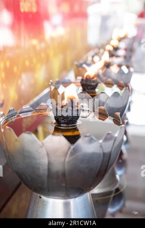 Fiamma di candela gialla che brucia, olio che riempie di candela di metallo di stile tailandese nel tempio buddista Foto Stock