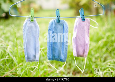 Maschera di stoffa fatta a mano, splendidamente colorata, appendere al sole. Concetto di maschera che aiuta a prevenire la diffusione di un coronavirus (COVID-19). Primo piano, copia spac Foto Stock