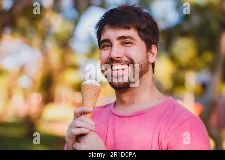 giovane uomo bello che mangia gelato nel parco Foto Stock