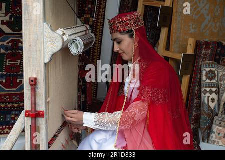Windsor, Berkshire, Regno Unito. 13th maggio, 2023. Una signora dall'Azerbaigian mostra agli ospiti come fanno i tappeti di lana a mano. È stata un'altra giornata intensa al Royal Windsor Horse Show nei giardini privati del Castello di Windsor. Quest'anno lo spettacolo celebra il 80th° anniversario. Gli ospiti si sono divertiti a guardare i cavalli competere e un posto di shopping. Credit: Maureen McLean/Alamy Live News Foto Stock