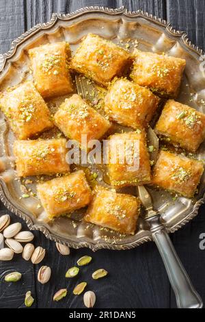 Il baklava è un dessert a strati di pasta di filo, ripieno di noci tritate e dolcificato con sciroppo o miele di primo piano sul piatto di legno Foto Stock
