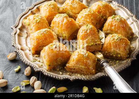 Baklava al pistacchio dolce a strati con primo piano al miele in un piatto sul tavolo. Orizzontale Foto Stock