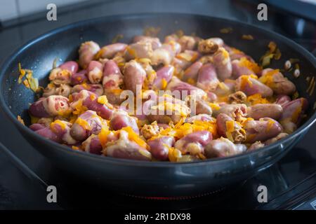 Cuori di pollo stufati con verdure in padella. Foto Stock