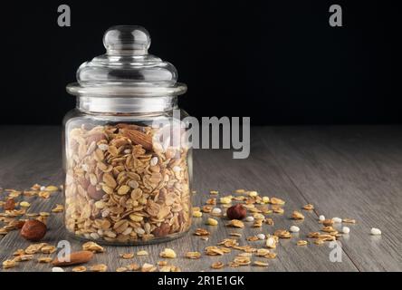 Granola fatta in casa in vaso sul tavolo da cucina, sana colazione di farina d'avena muesli, noci, semi e frutta secca. Foto Stock