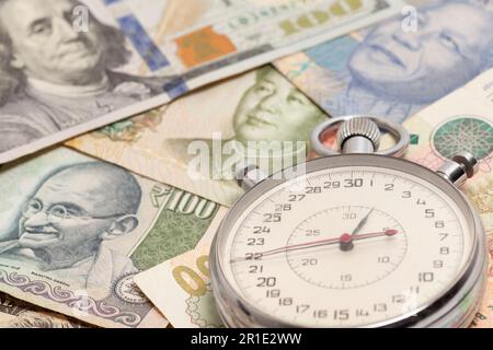 Cronometro con valute internazionali.. Il tempo è concetto di denaro. Foto Stock