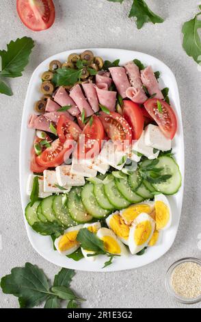 Insalata sana di cobb con prosciutto, formaggio feta, cetriolo, pomodoro, olive e uova. Pranzo chetogenico. Vista dall'alto, dall'alto Foto Stock