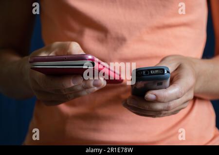 nelle mani di una ragazza pulsante vecchio telefono cellulare e toccare nuovo telefono primo piano Foto Stock