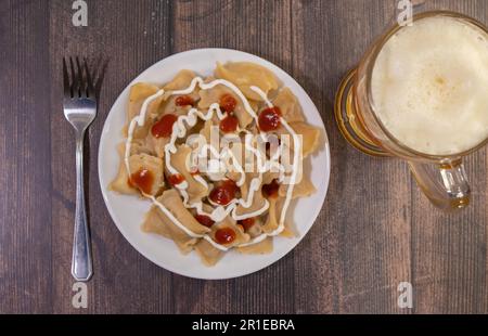 Deliziosa casa calda ceco tradizionale gulasch di manzo servita con cotti al vapore Gnocchi cechi o knedliky sulla piastra nera sul tavolo in legno con vetro di bee Foto Stock