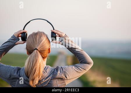 Donna con cuffie che si prepara per correre su strada. Allenamento e fitness all'aperto Foto Stock