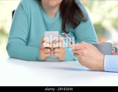 Due amici che usano i loro smartphone in un bar Foto Stock