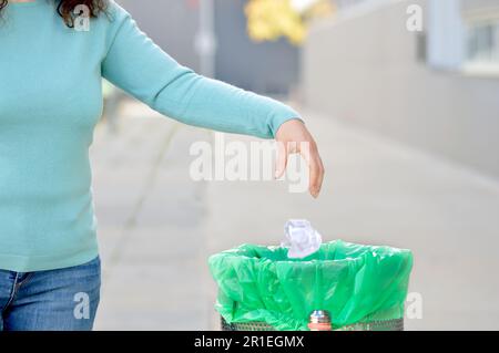 Civic donna gettando spazzatura in un cestino una città Foto Stock