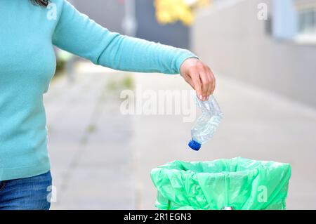 Civic donna gettando spazzatura in un cestino una città Foto Stock