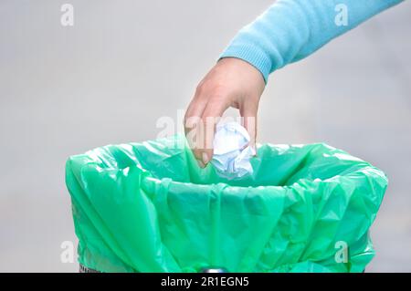 Civic donna gettando spazzatura in un cestino una città Foto Stock