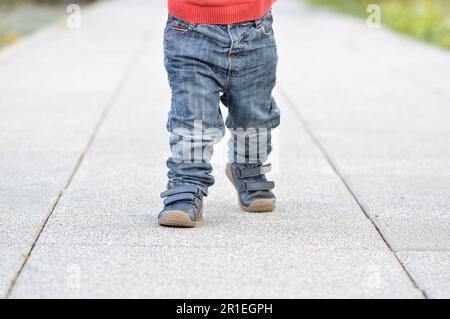 Immagine ritagliata delle gambe di un bambino che cammina per strada Foto Stock