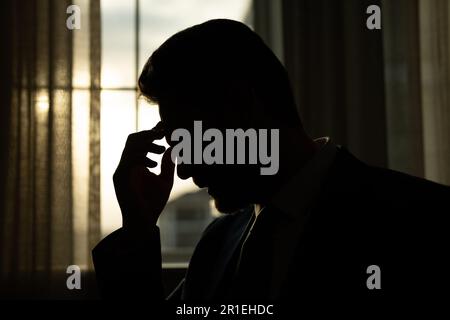 Uomo stanco che soffre di mal di testa dopo il lavoro al computer, esausto con gli occhi chiusi che toccano la testa, alleviare il dolore, emicrania. Problemi aziendali Foto Stock