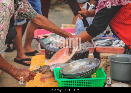 Fornitori che preparano i pesci per il cliente al mercato del pesce a Kedonganan - Passer Ikan, Jimbaran Beach, Bali Foto Stock