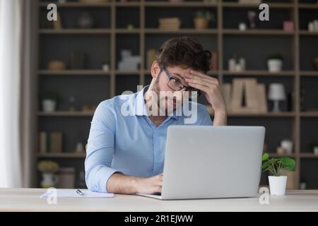 Uomo freelancer triste stanco che ottiene i problemi con il laptop Foto Stock