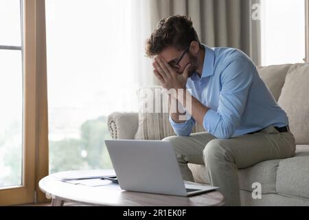 Ha sottolineato l'uomo d'affari freelance infelice seduto sul divano di casa Foto Stock