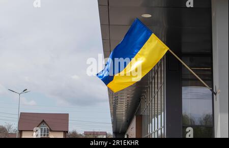 La bandiera nazionale dell'Ucraina batte nel vento su un paletto, su un edificio. Colori blu e giallo sulla bandiera Ucraina. Bandiera dell'Ucraina sulla f Foto Stock