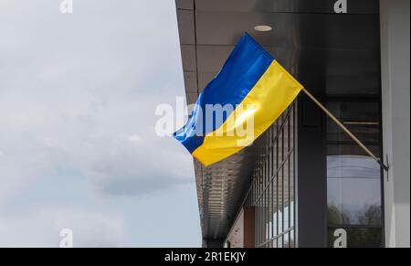 La bandiera nazionale dell'Ucraina batte nel vento su un paletto, su un edificio. Colori blu e giallo sulla bandiera Ucraina. Bandiera dell'Ucraina sulla f Foto Stock