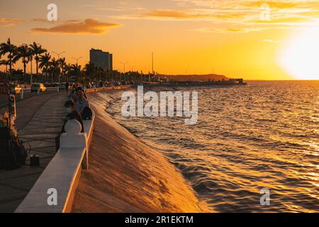 I residenti si rilassano lungo la malecón a Campeche, Messico, al tramonto Foto Stock