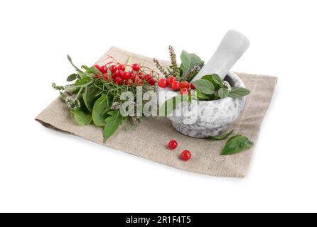 Malta di stoffa e marmo con diverse erbe, bacche e pestello su fondo bianco Foto Stock