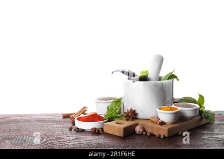 Mortaio e spezie diverse su tavola di legno su sfondo bianco. Spazio per il testo Foto Stock