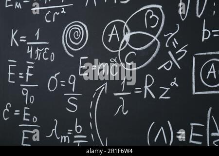 Diverse formule matematiche scritte con il gesso sulla lavagna Foto Stock