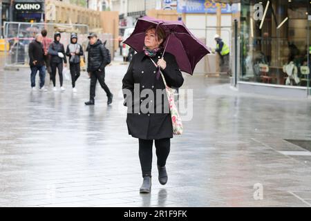 Londra, Regno Unito. 12th maggio, 2023. Una donna si rifugia sotto un ombrello durante il tempo umido nel centro di Londra. Le temperature incontrate dell'Ufficio a Londra raggiungono i 20 gradi Celsius il sabato dopo la pioggia, il tuono e l'illuminazione di questa settimana. Credit: SOPA Images Limited/Alamy Live News Foto Stock