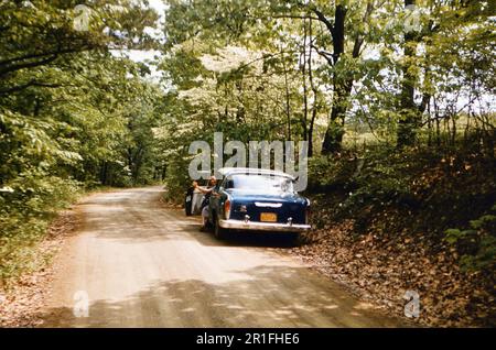 Autista parcheggiato lungo una strada sterrata rurale ca. 1950s Foto Stock